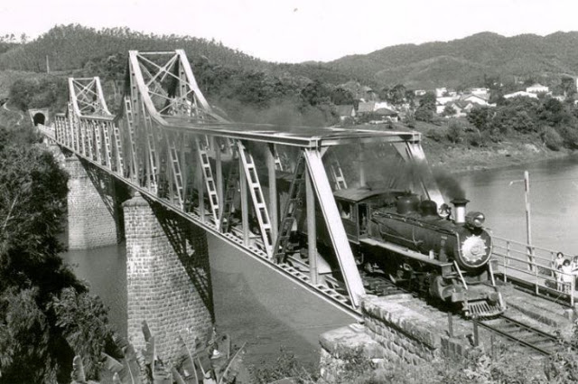Locomotiva a vapor atravessando ponte ferroviária sobre o rio